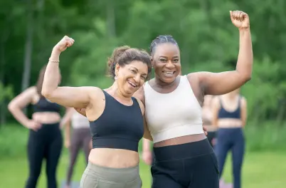 Two woman showing their muscles in an outside garden. This shows you how to look and feel good!