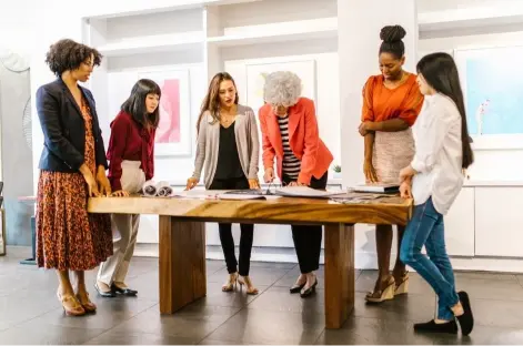 My New Look consultants stand around a table consulting on a woman's image